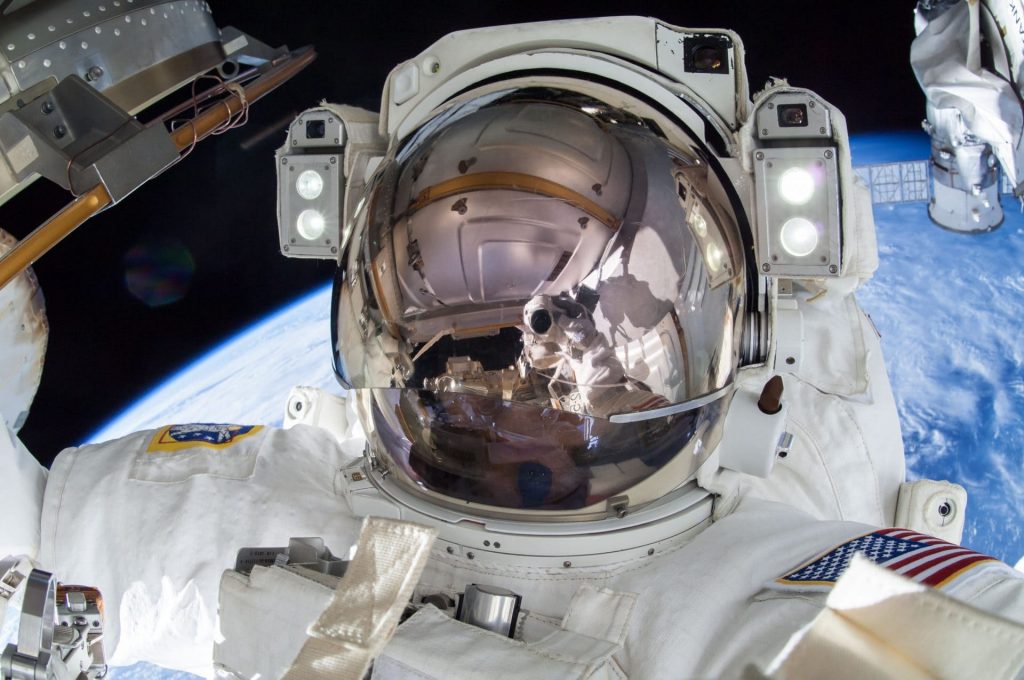 Terry Virts, in white space suit with a blue Earth behind him